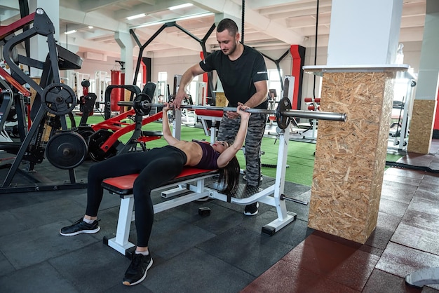 Attraktive junge männliche Trainer und weibliche Kunden, die im Fitnessstudio trainieren