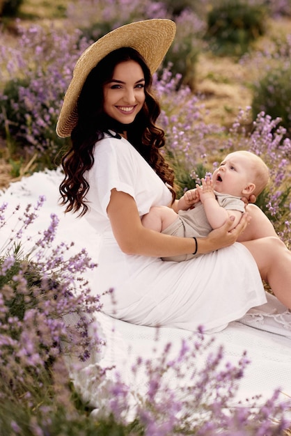 Attraktive junge Mutter, die mit ihrem Baby auf einem Lavendelgebiet spielt