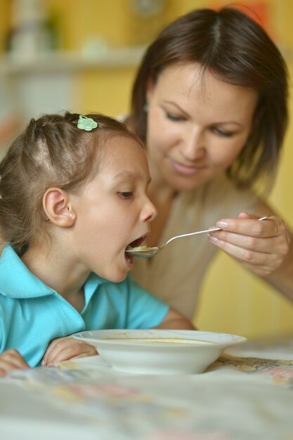 Attraktive junge Mutter füttert ihre Tochter mit Suppe