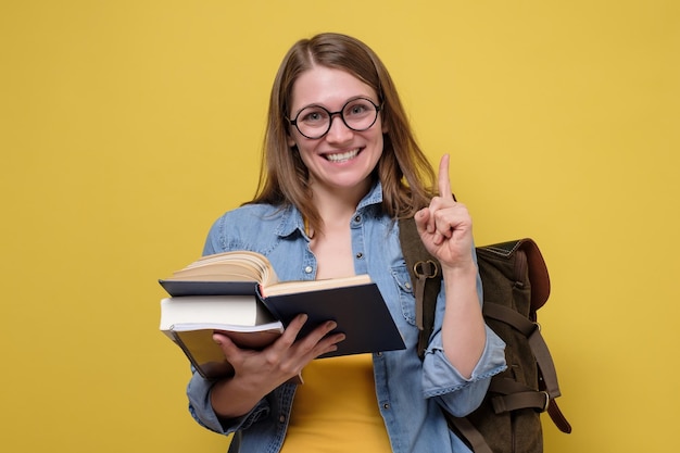 Attraktive junge Studentin, die einen Stapel Bücher trägt