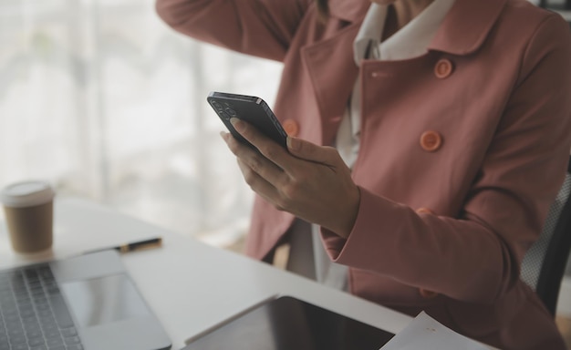 Attraktive lächelnde junge asiatische Geschäftsfrau, die zu Hause im Büro arbeitet Asiatische Frau, die an einem Laptop-Computer mit Tablet arbeitet