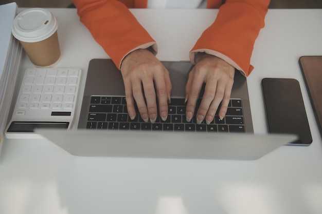 Attraktive lächelnde junge asiatische Geschäftsfrau, die zu Hause im Büro arbeitet Asiatische Frau, die an einem Laptop-Computer mit Tablet arbeitet