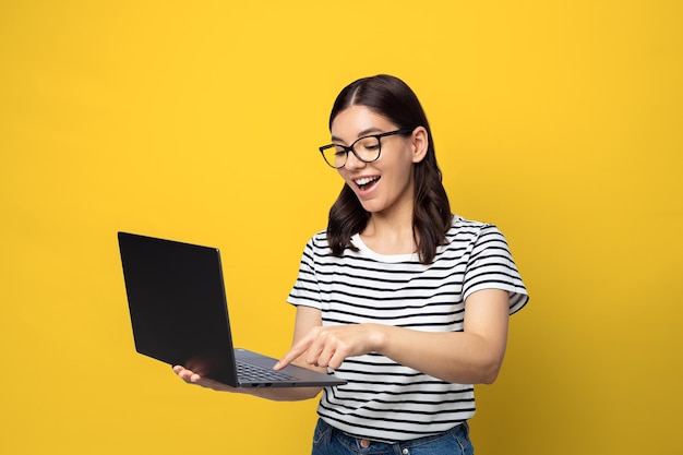 Attraktive multiethnische Studentin mit Brille glücklicher Ausdruck mit einem Laptop