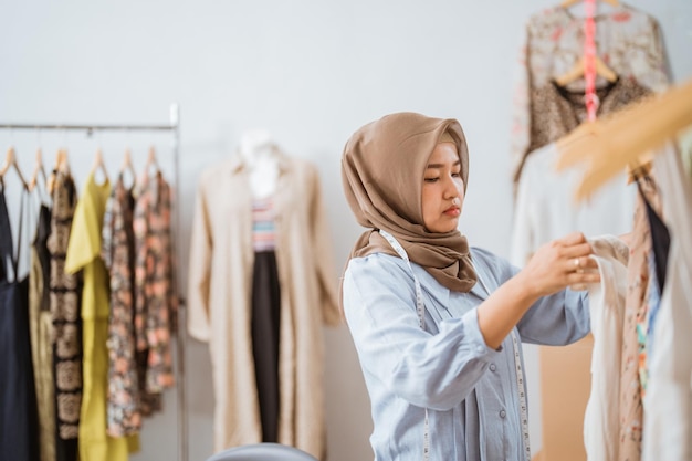 Attraktive muslimische Modedesignerin, die ihr Kleiderprodukt in ihrem Büro überprüft