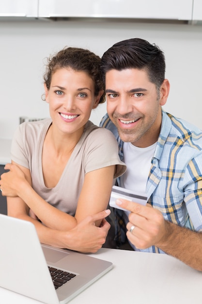 Attraktive Paare, die zusammen Laptop verwenden, um online zu kaufen