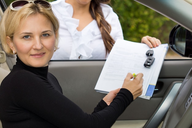 Foto attraktive reife blonde frau, die ein neues auto kauft