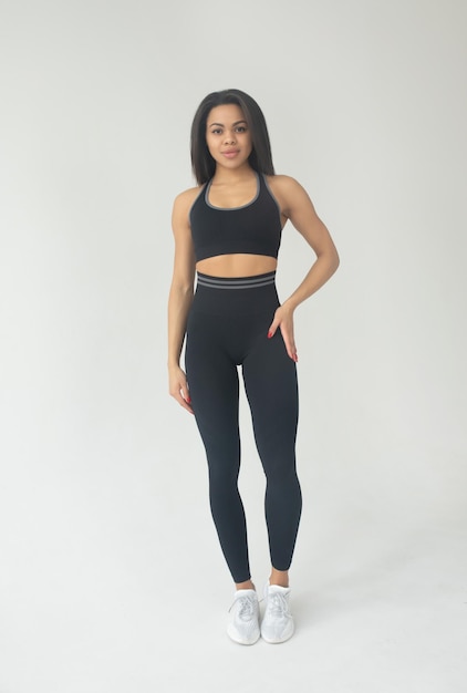 Attraktive schwarze Afroamerikanerin in farbigen Leggings und Top-Fitness-Outfit