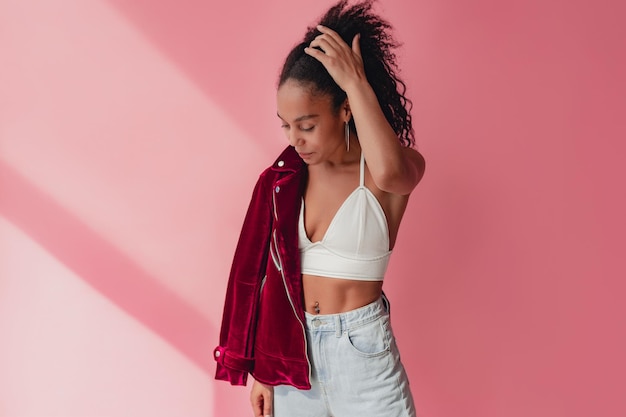 Attraktive schwarze afroamerikanerin in stylischem outfit auf rosa hintergrund
