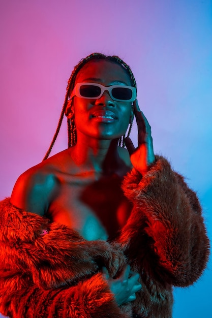 Attraktive schwarze ethnische Frau mit Zöpfen mit roten und blauen LED-Leuchten fangen Tänzerin mit Sonnenbrille ein