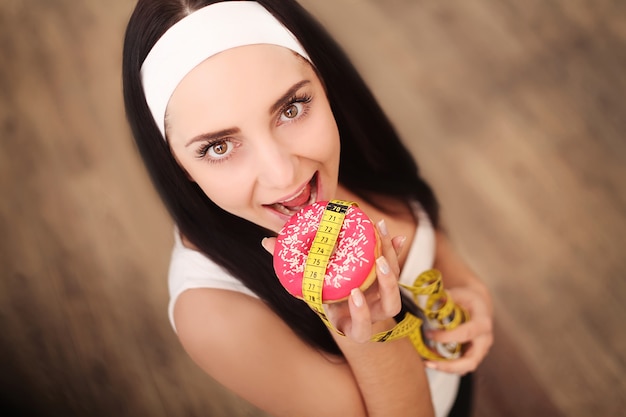 Attraktive sexy Frau der Brünetten, die leckeren Donut isst