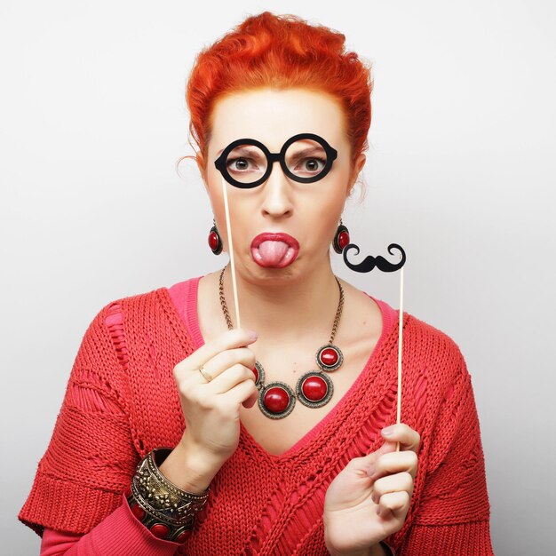Attraktive spielerische junge Frau mit Schnurrbart und Brille auf einem Stock bereit für eine Party