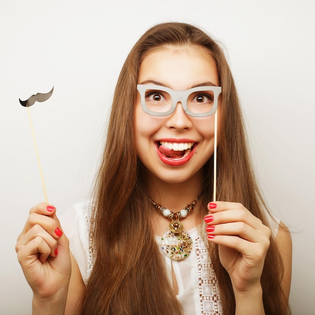 Attraktive spielerische junge Frau mit Schnurrbart und Brille auf einem Stock bereit für eine Party