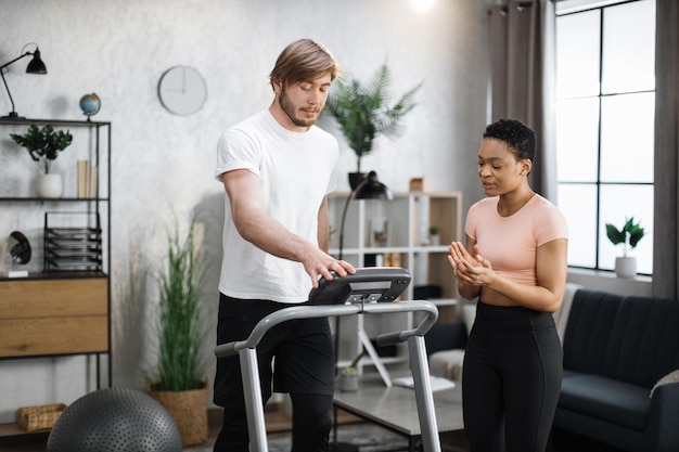 Attraktive, sportlich fitte Menschen, die die Laufstrecke nutzen und den Modus für das Sporttraining auswählen