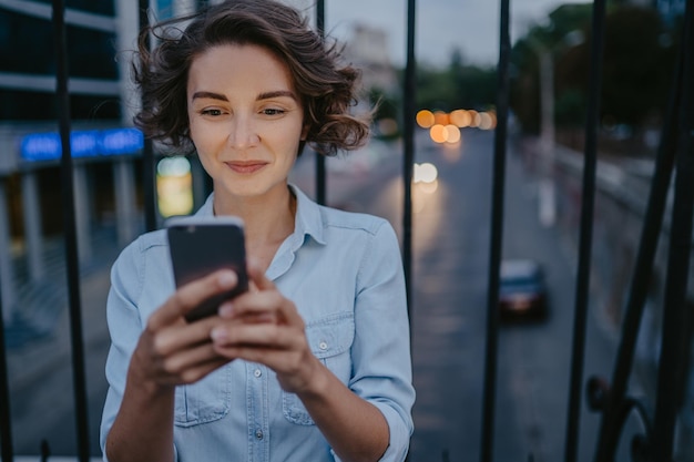 Attraktive stilvolle Frau, die mit dem Smartphone auf der Straße spazieren geht