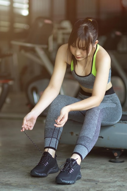 Attraktive und schöne Fitnessfrau in Sportkleidung, die ihre Schuhe bindet, um im Fitnessstudio trainieren zu können.