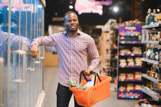 Foto attraktiver afroamerikanischer mann, der in einem supermarkt einkaufen geht