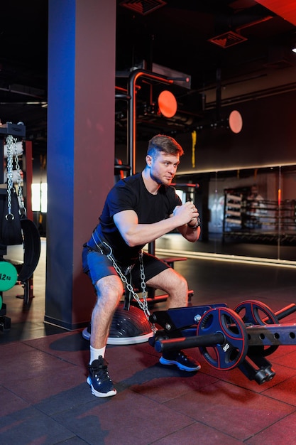 Attraktiver erwachsener Mann, der im Fitnessstudio Übungen macht und Gewichte hebt. Sporttraining im Fitnessstudio