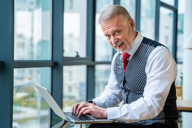 Attraktiver Geschäftsmann, der in einem modernen Büro arbeitet Glücklicher Unternehmer des Lebensstils, der am Schreibtisch sitzt