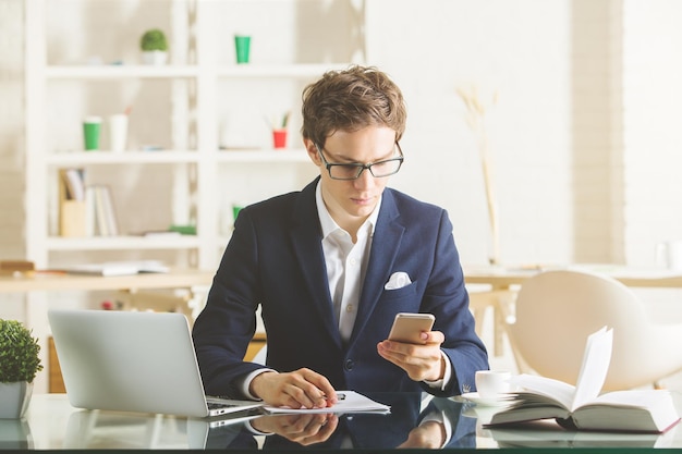 Attraktiver Geschäftsmann mit Laptop und Smartphone