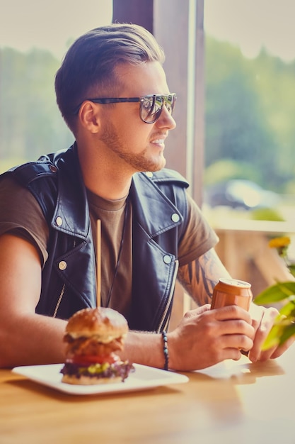 Attraktiver Hipster in Lederjacke, der einen veganen Burger isst.