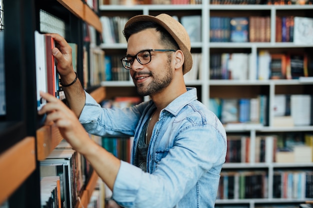 Attraktiver junger männlicher Student, der Bücher in der Buchhandlung auswählt