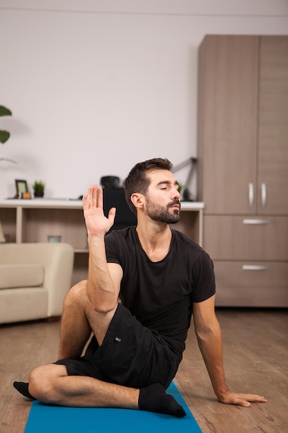 Attraktiver junger Mann, der den halben Lord der Fische in Yoga-Pose macht. Fitter junger Mann.