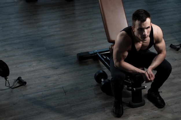 Attraktiver junger Mann, der sich nach dem Training im Fitnessstudio ausruht