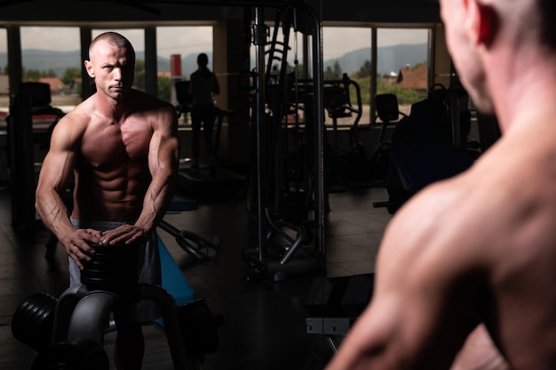 Attraktiver junger Mann, der sich nach dem Training im Fitnessstudio ausruht