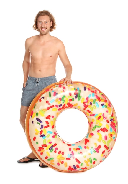 Attraktiver junger Mann in Badebekleidung mit aufblasbarem Ring des Donuts auf weißem Hintergrund