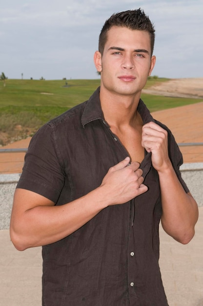 Foto attraktiver junger mann mit aufgeknöpftem hemd im freien