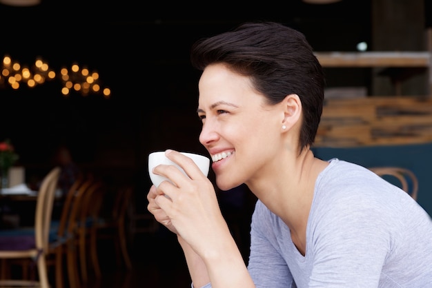 Attraktiver junger trinkender Kaffee der Frau am Kaffee