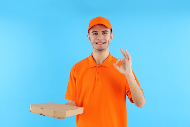 Attraktiver Lieferbote mit Pizzaschachtel auf blauem Hintergrund