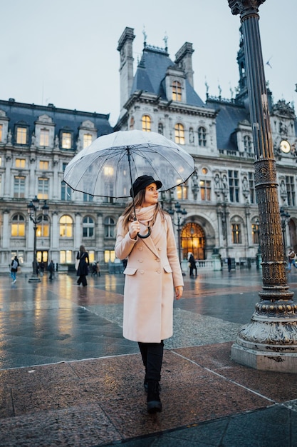 Attraktiver Mädchenreisender mit transparentem Regenschirm genießt die Aussicht
