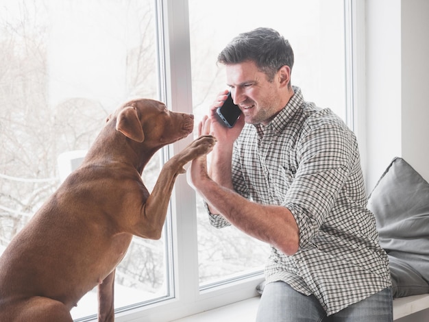 Attraktiver Mann, der am Telefon spricht und liebenswerter Welpe