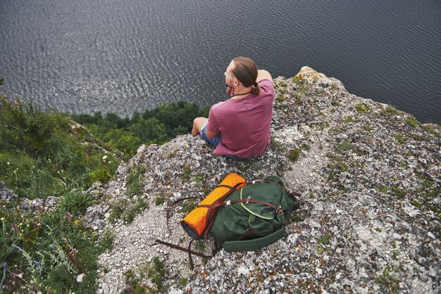 Attraktiver Mann, der den Blick auf die Berglandschaft über der Wasseroberfläche genießt. Abenteuerurlaubskonzept