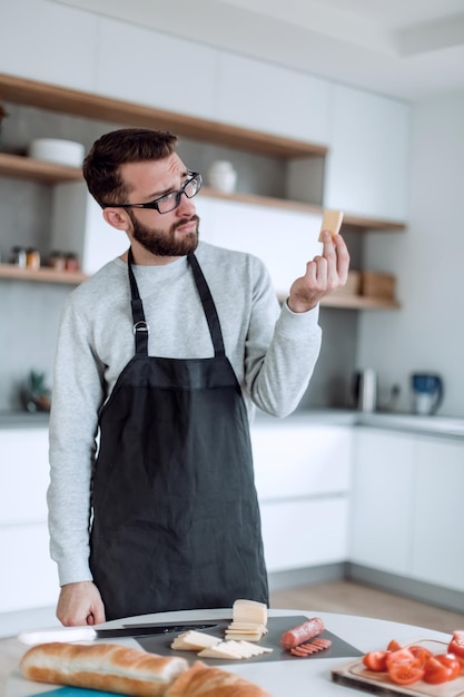 Attraktiver Mann, der ein Stück köstlichen Käse zeigt