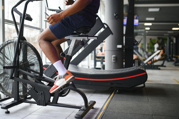 Attraktiver Mann im Fitnessclub trainiert auf dem Fahrrad