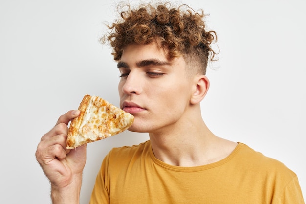 Attraktiver Mann in einem gelben T-Shirt, der Pizza isst. Lebensstil unverändert