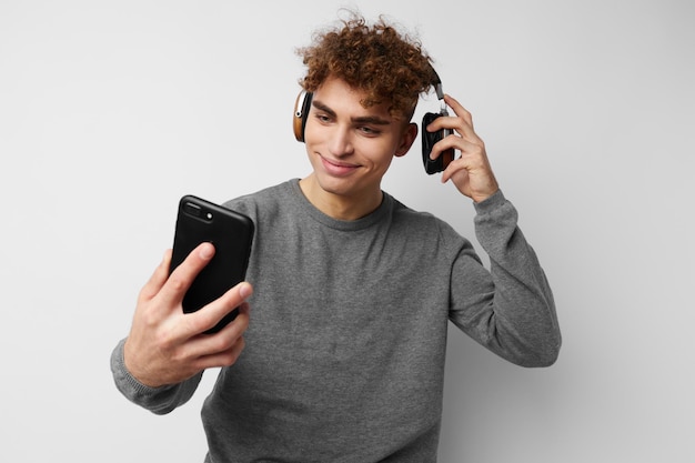 Attraktiver Mann mit einem Telefon in der Hand, das Musik im hellen Hintergrund der Kopfhörer hört