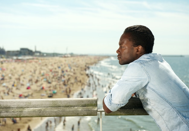 Attraktiver schwarzer Mann, der am Strand sich entspannt