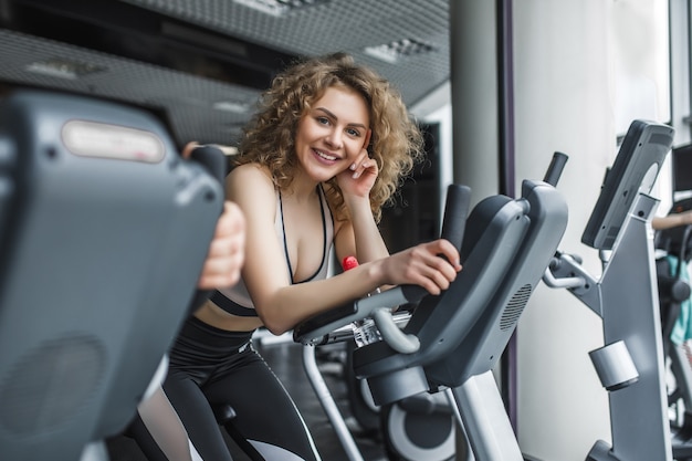 Attraktiver Trainer der jungen Frau, der auf Laufband im Fitnessstudio läuft