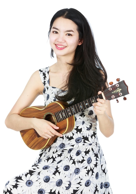 Attraktives asiatisches Mädchen, das Ukulele spielt