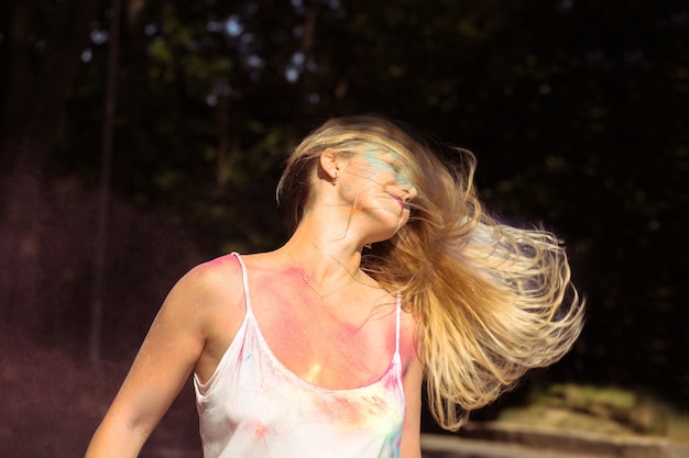 Attraktives blondes Mädchen mit Wind im Haar posiert beim Holi-Festival