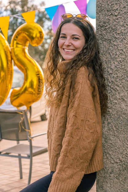 Foto attraktives braunäugiges mädchen in orangefarbenem pullover, das mit einem lächeln auf goldenem hintergrund in die kamera schaut