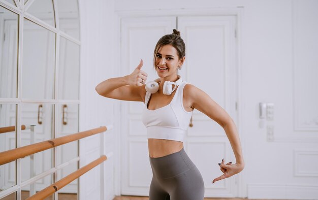 Foto attraktives brünettes hispanisches mädchen in sportkleidung zeigt zufrieden daumen nach oben auf gesäß