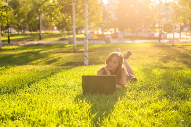 Attraktives brünettes Teenagermädchen, das draußen Spaß mit Laptop hat