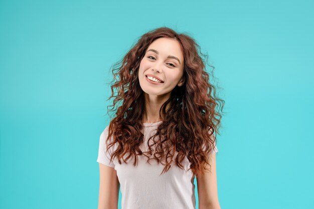 Attraktives Brunettemädchen mit dem lockigen Haar und einem glücklichen freundlichen Lächeln