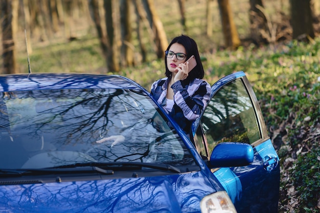 Attraktives Fahrermädchen schaut aus der offenen Tür des Autos und der Unterhaltung am Telefon