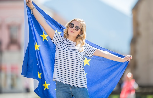 Attraktives glückliches junges Mädchen mit der Flagge der Europäischen Union.