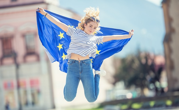 Attraktives glückliches junges Mädchen mit der Flagge der Europäischen Union.